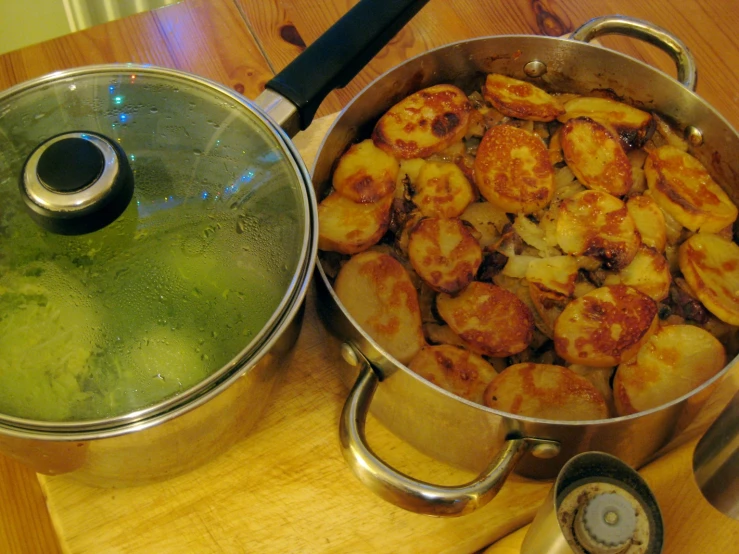 some food on a wooden table next to a metal pot