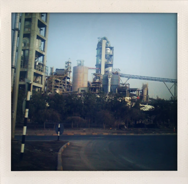 industrial plant in background and street lamp with man on side of road