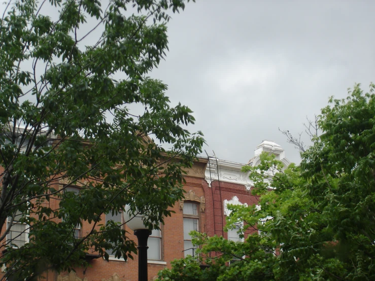 a red brick building has a tower and trees around it