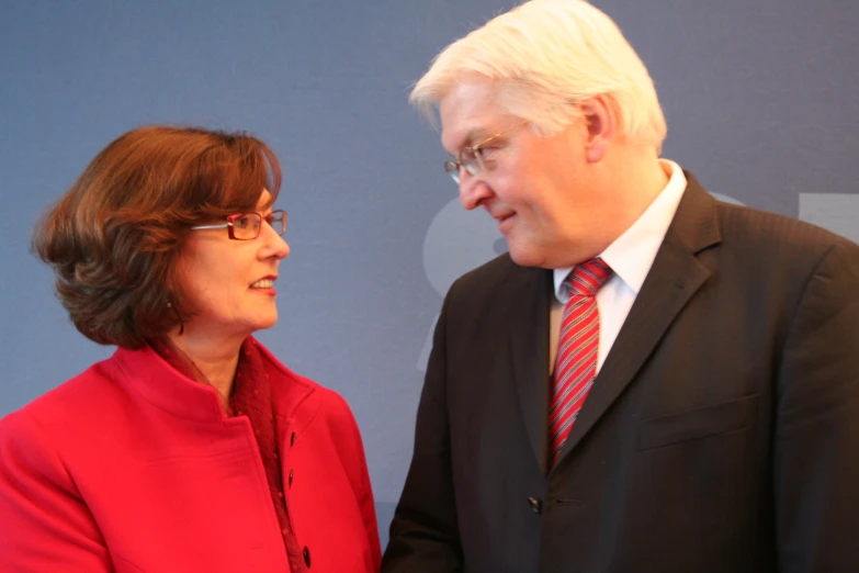 two people looking at each other near a blue wall