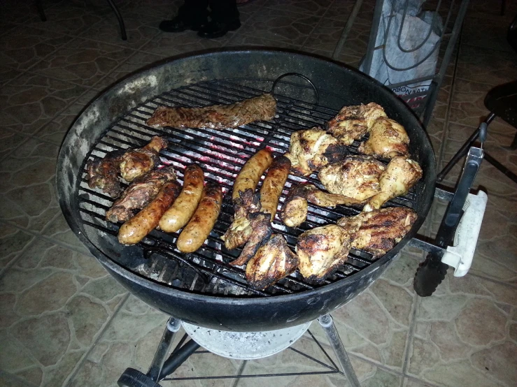 a large black grill with many chicken feet cooking on it