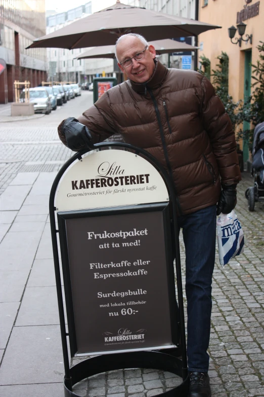 man posing under a sign in front of a street