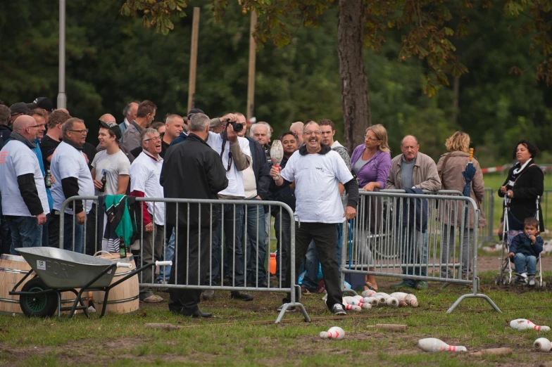 many people are standing behind bars that are blocking the road