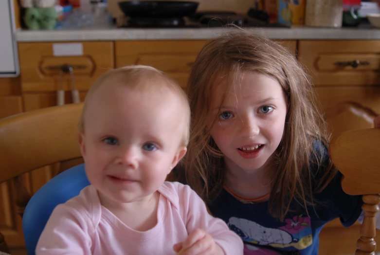 two little girls sitting at the table with a smile on their face