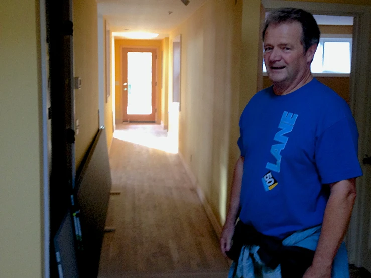 a man wearing a blue shirt and smiling in the hallway
