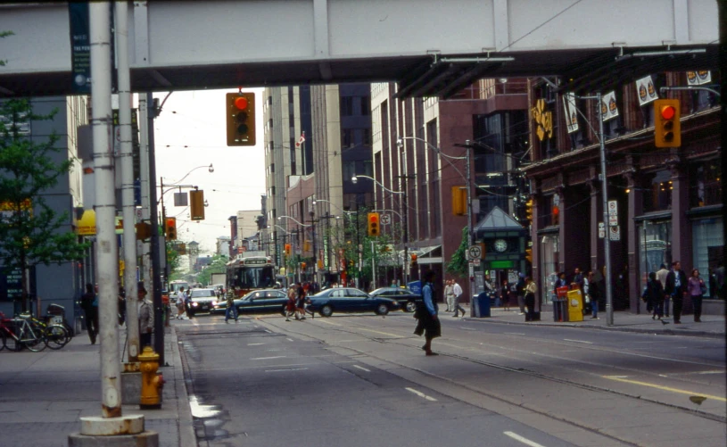 an intersection with traffic lights on one side and people walking the other