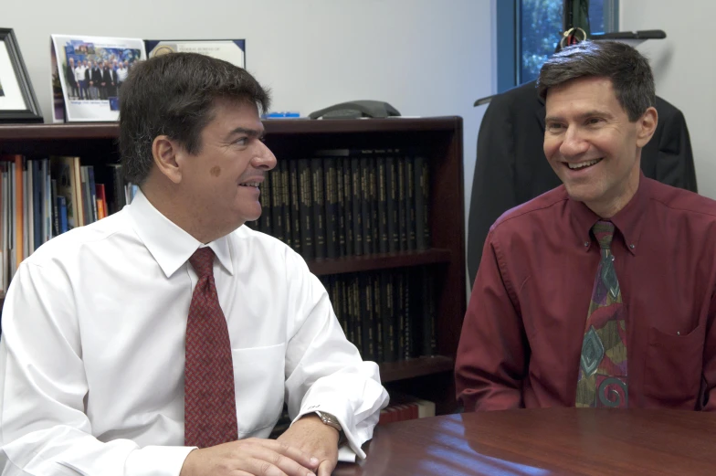 two men sitting next to each other smiling and laughing