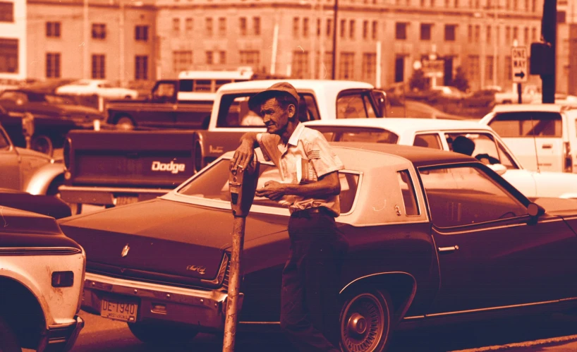 man leaning on car in crowded urban street