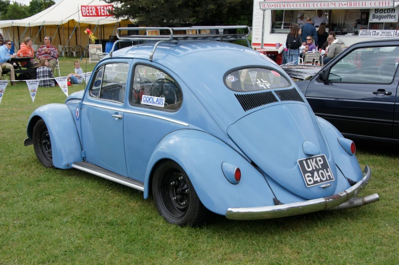 an old volkswagen type car on display at an outdoor show
