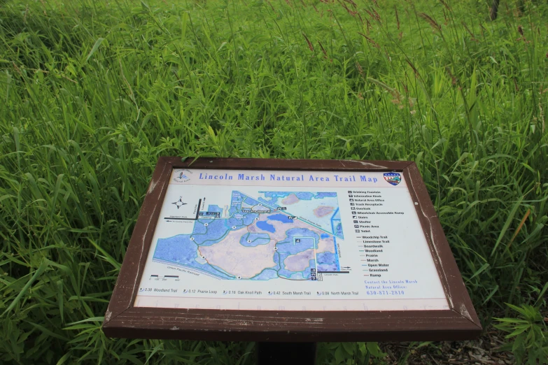 a sign is shown in tall grass by a trail