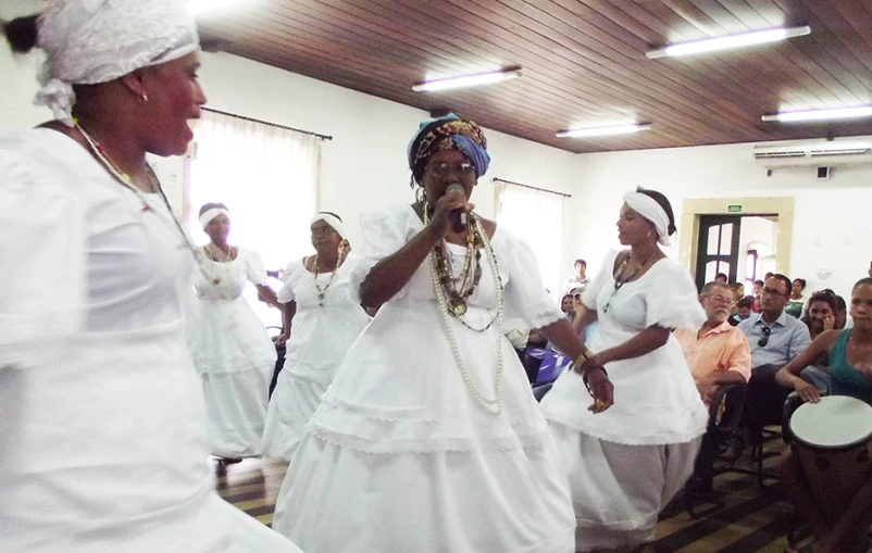 a group of women in dress singing and playing on stage