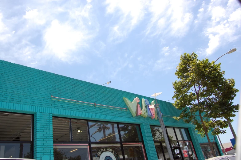 a turquoise brick building with an american flag hanging over the entrance