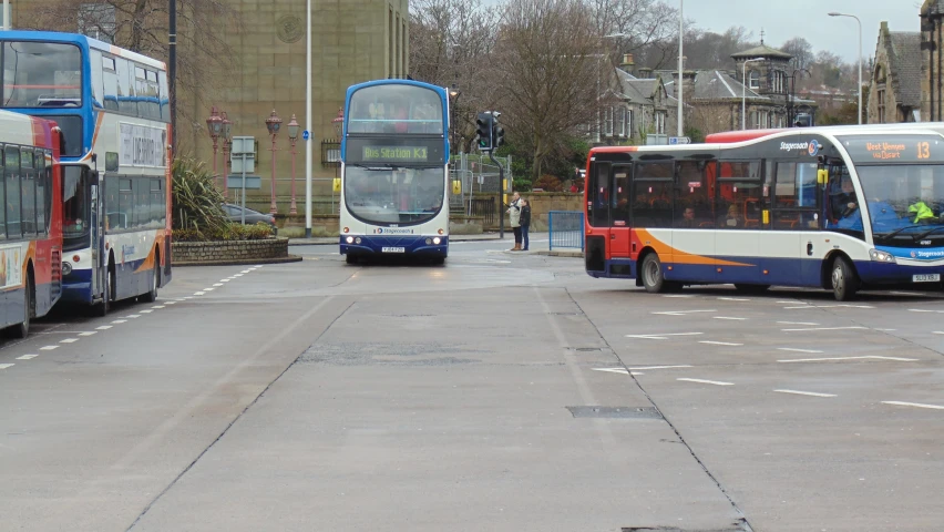 some red and blue buses are traveling down the street