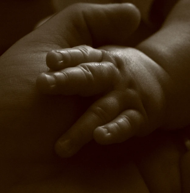 a man's hands is holding a sleeping newborn