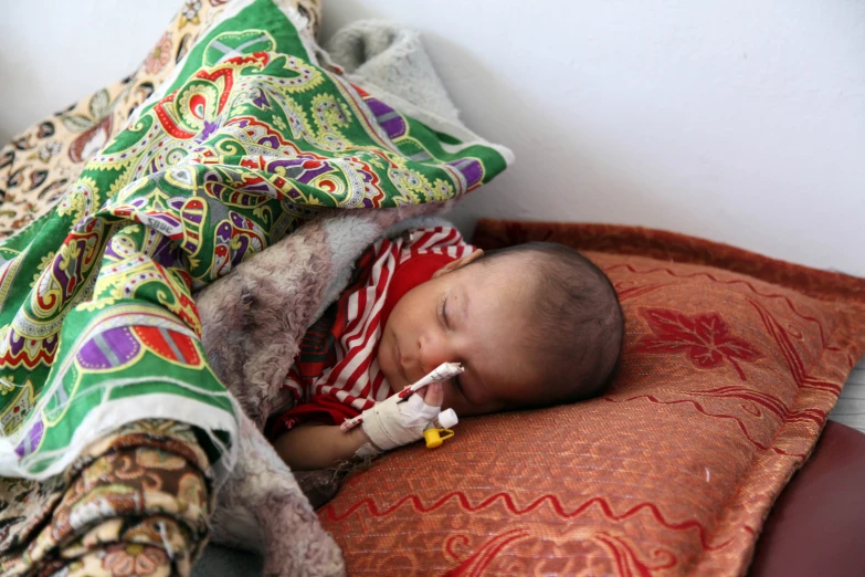 a baby sleeps on a blanket and lays in the corner