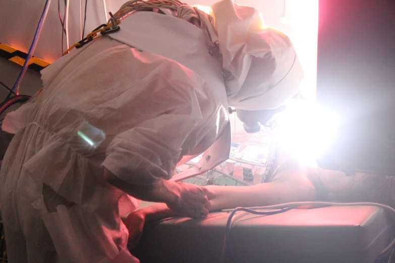 a man in lab coat performing a metal work