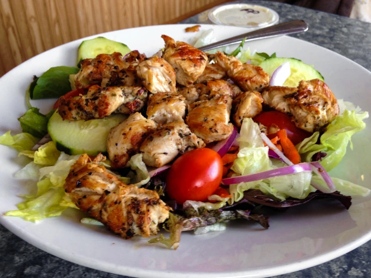 a plate with chicken, lettuce and cherry tomatoes