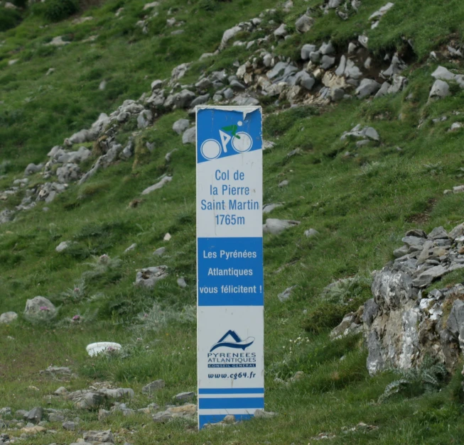 a sign sits in the grass on top of a hill