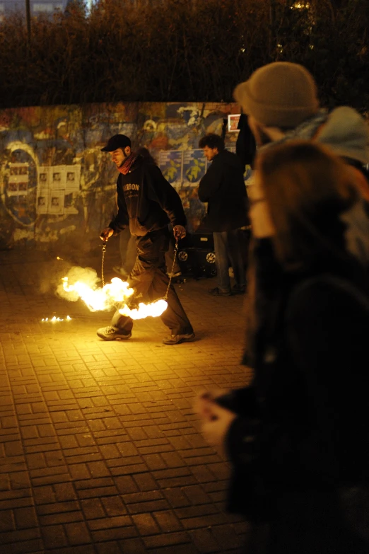 people stand in the dark while two women use fire to burn them