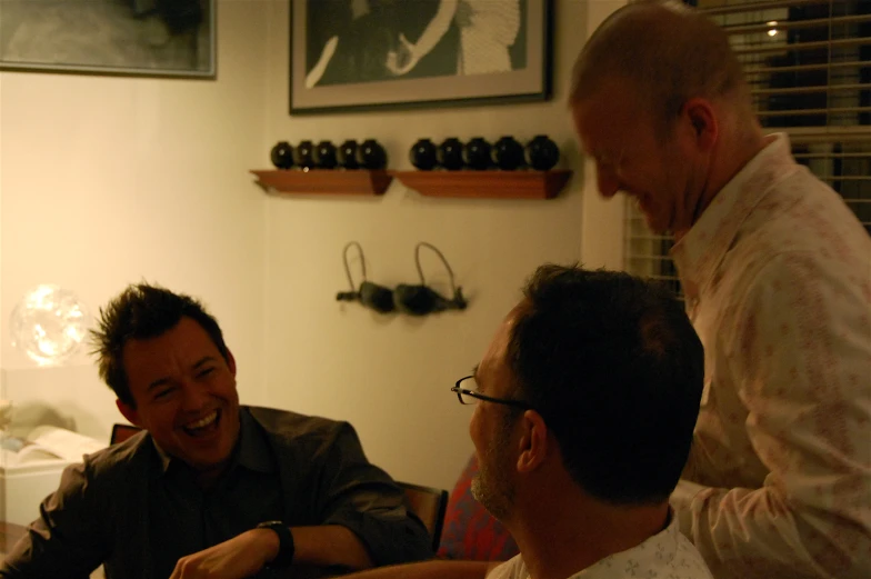 three people are laughing at each other in a room