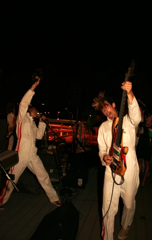 man in white suit with a guitar posing for the camera