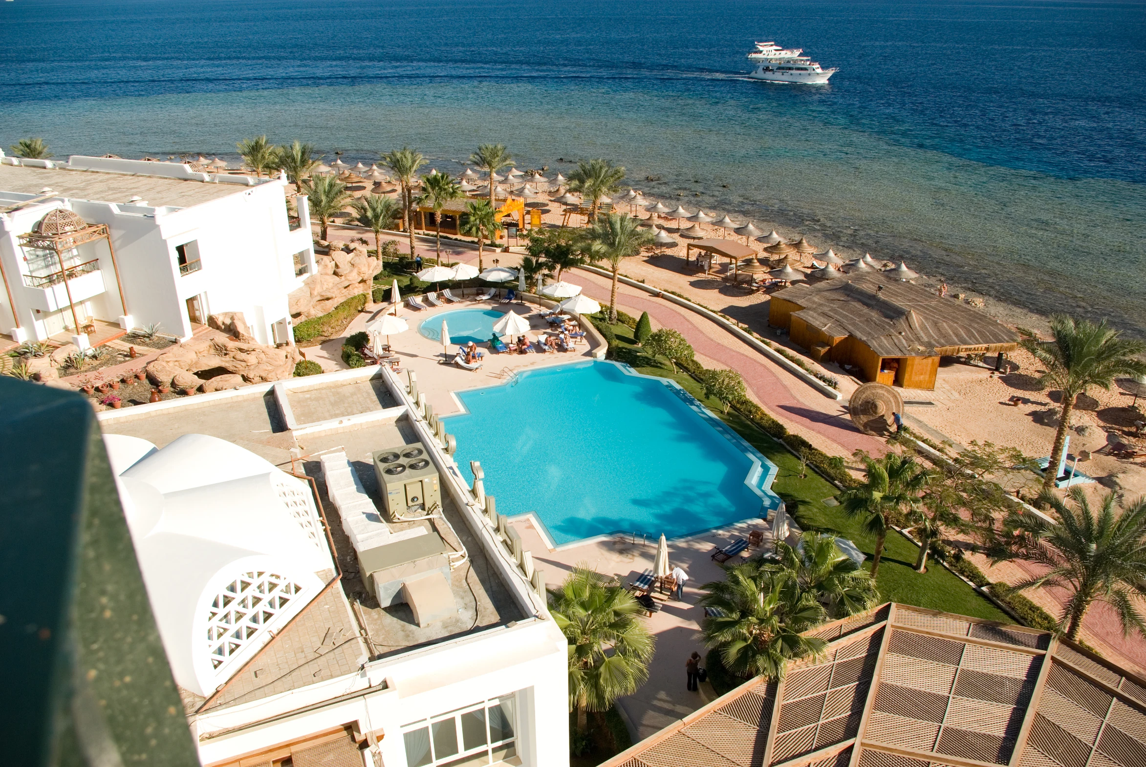 an aerial s of some resort style pools next to a body of water