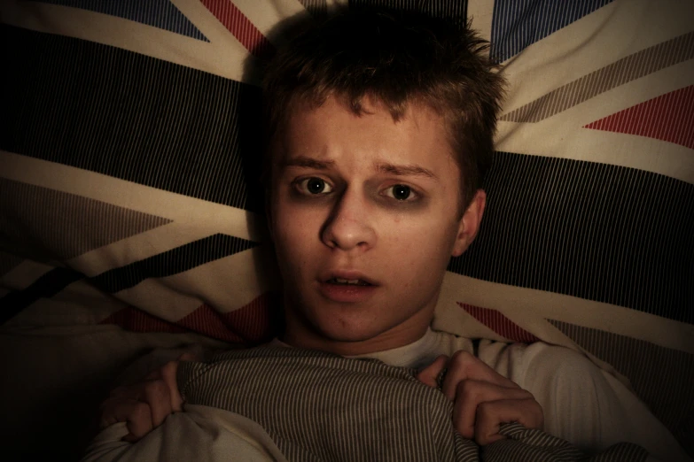 a man looking at the camera with his shirt up and british flag in the background