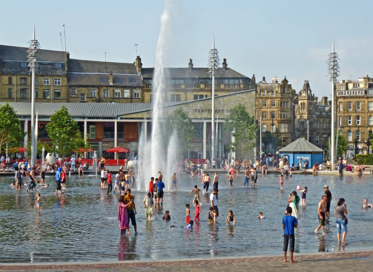 a group of people standing around the water fountain