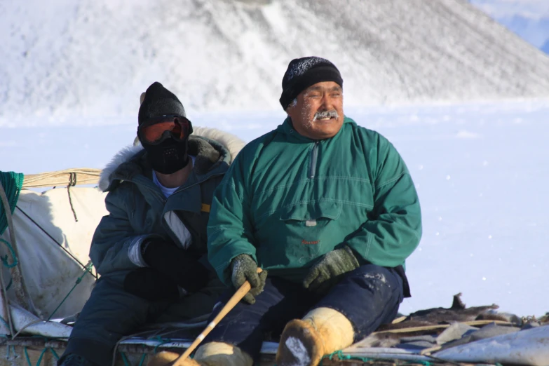 two people sitting on top of a sled
