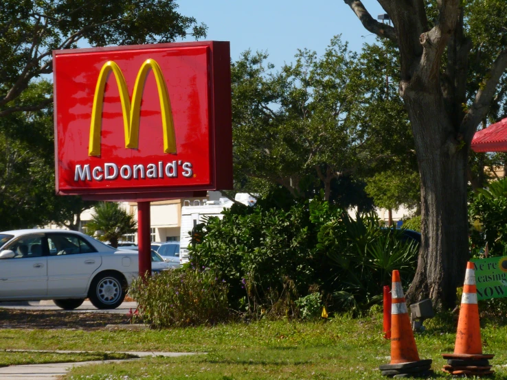 a mcdonald's sign at an intersection with an orange cone