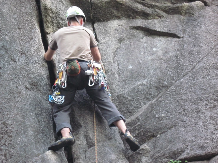 a man in climbing gear is going up a mountain side