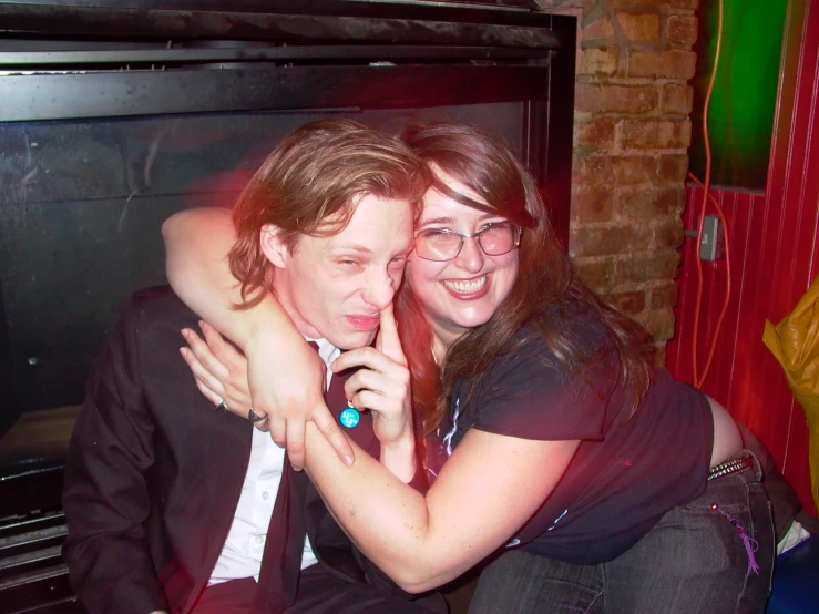 the man and woman are posing together in front of a fireplace