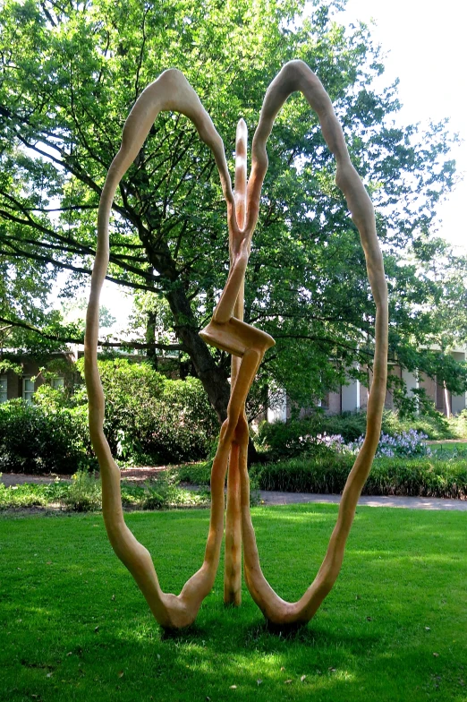 three sculptures in the grass with a tree in the background