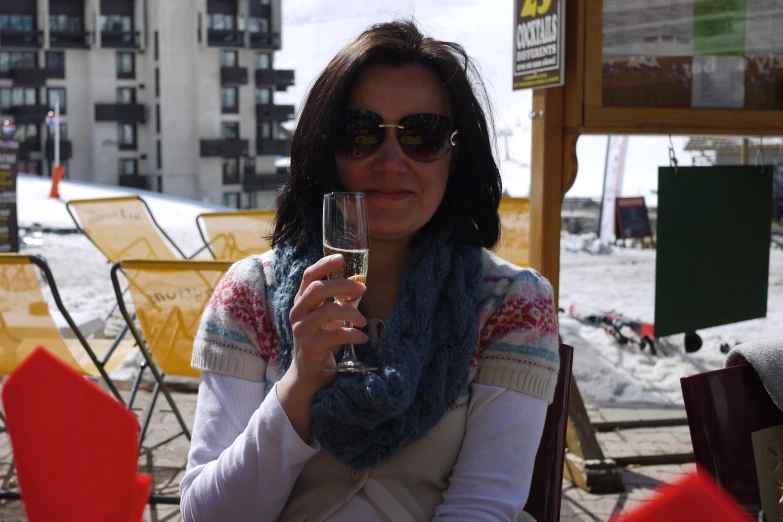 woman with scarf holding glass of wine outside