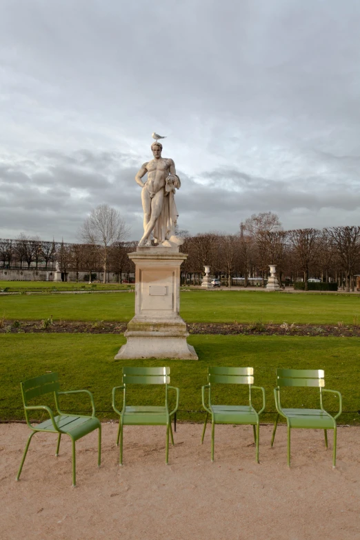 a statue is next to lawn chairs in the middle of a field