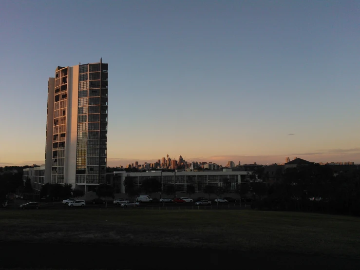 a skyscr on top of a hill with a few cars parked in front of it