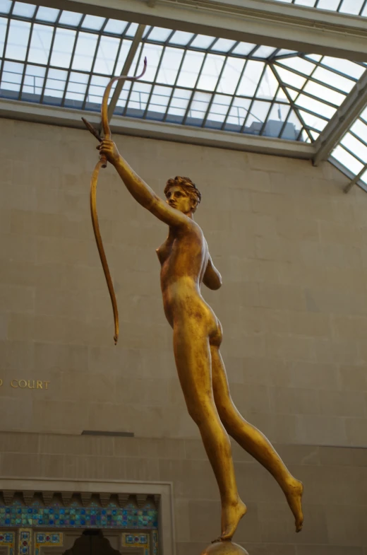 there is a golden statue of a lady with a bow and arrow