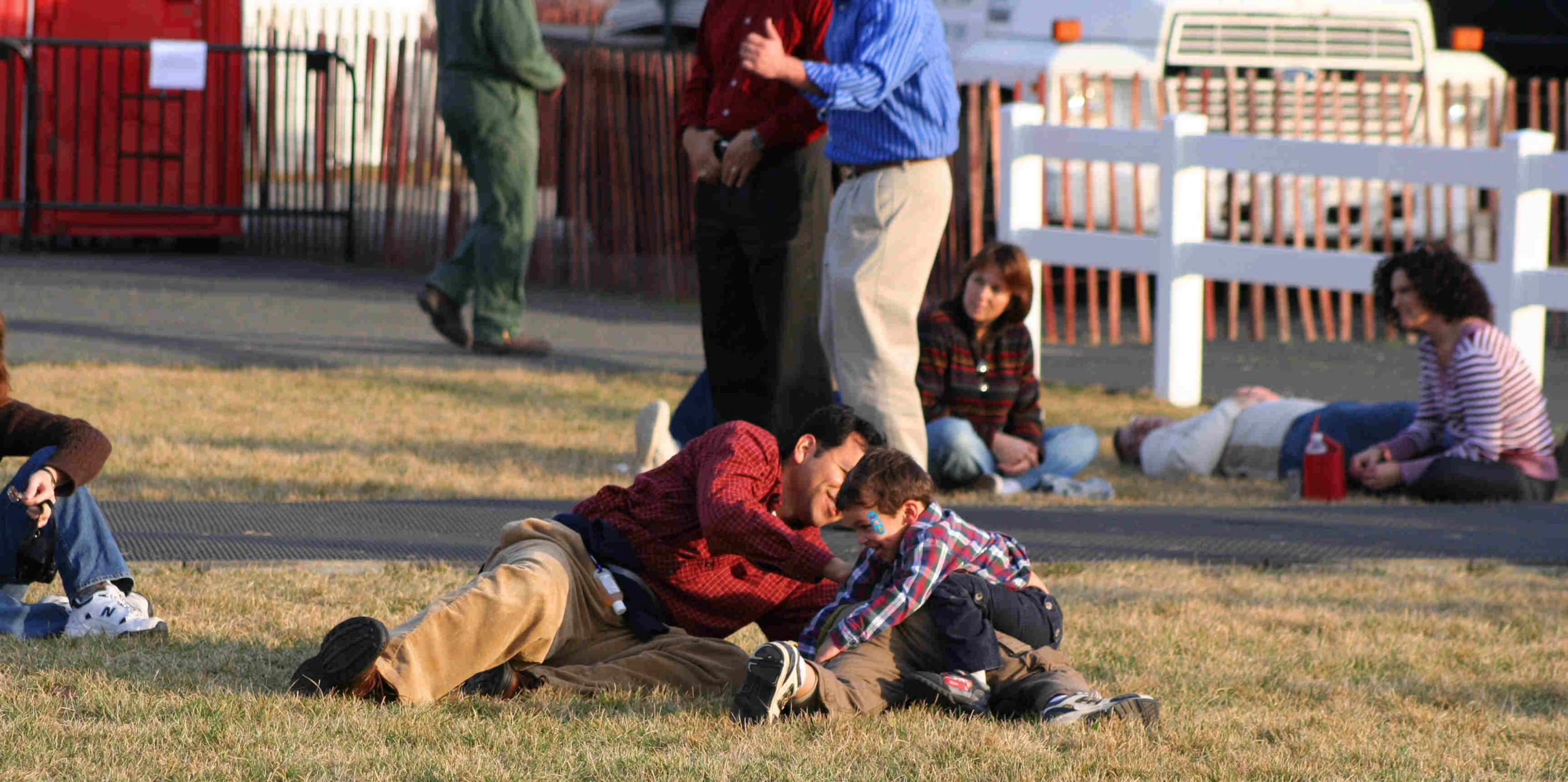 a man sitting in the grass while other people talk