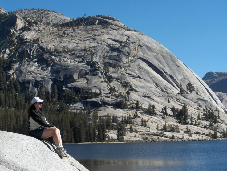 a woman sitting on a rock looking over the top