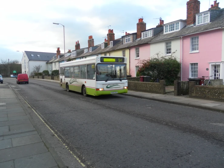 city bus turning a corner in front of a pink house