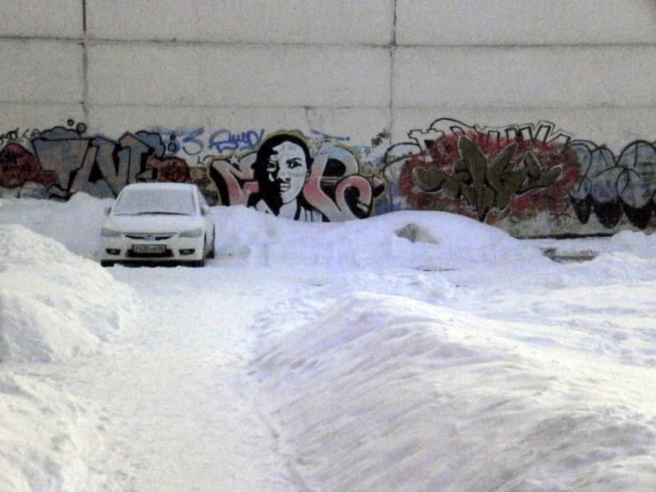 a car driving down a snowy street past graffiti