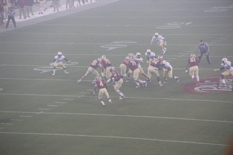 two teams of football players on field with fog in the air
