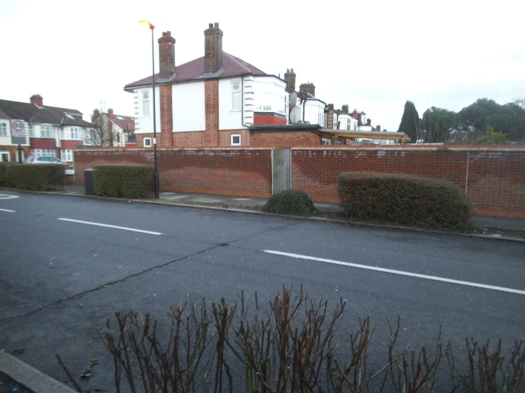 a view of a street corner showing a brick wall and a building with towers