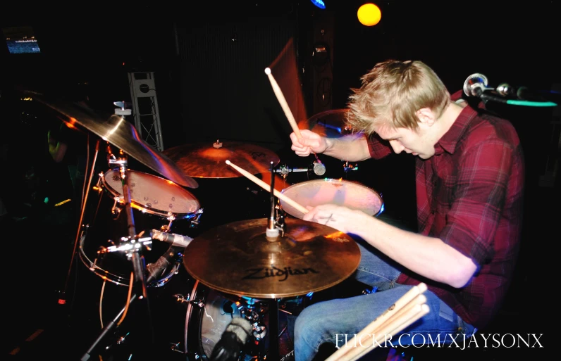 a man playing drums in a band at night