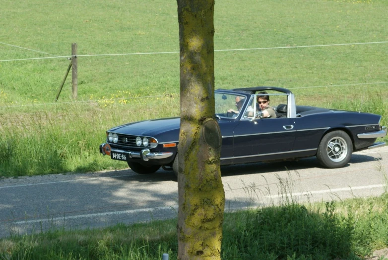 a person driving a convertible with the driver in the cab