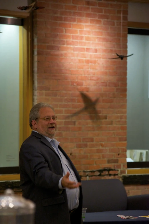 man wearing glasses talking in front of a clock