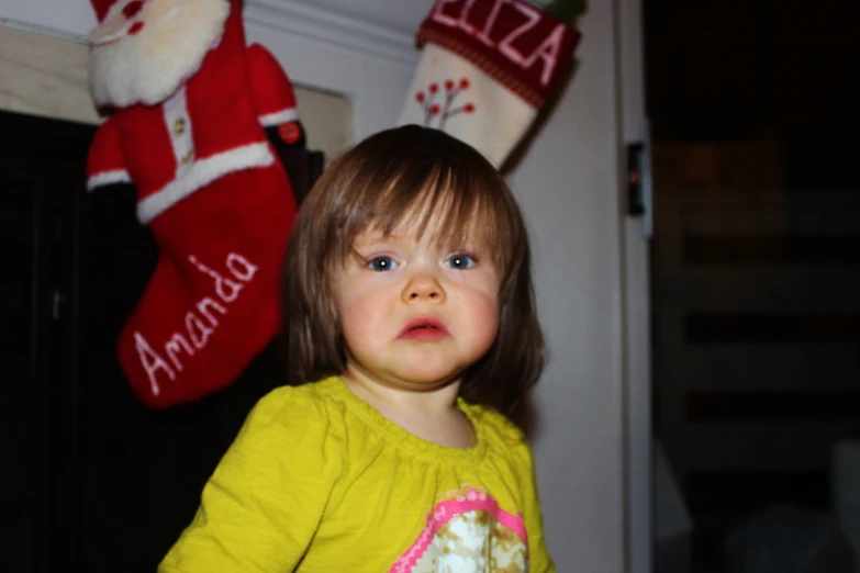 the little girl is standing next to two santa stockings