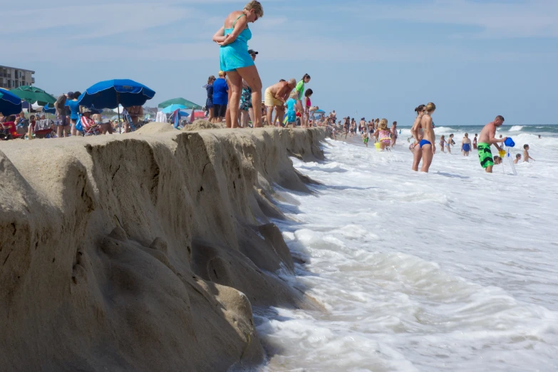 a beach with many people on it and waves crashing onto the sand