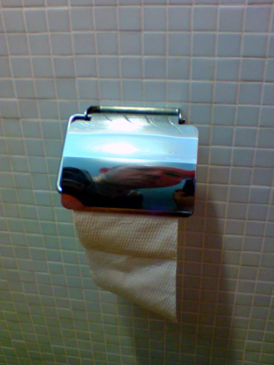 a chrome toilet roll holder mounted on a white tiled wall