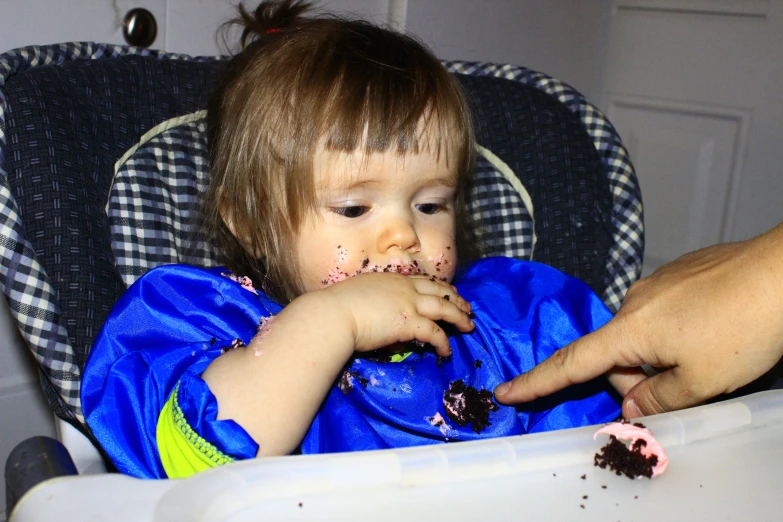 the child is sitting in the high chair with cake all over their face